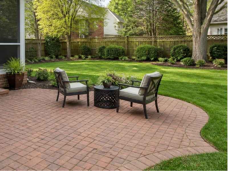 Brick patio with outdoor seating beside a green backyard in Madison, Alabama.