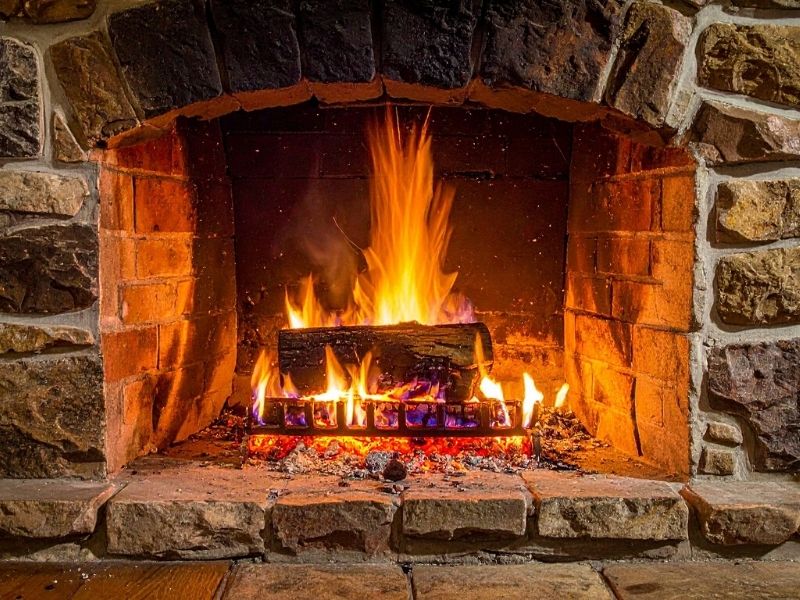 Natural stone fireplace hearth with burning logs showing durable masonry materials