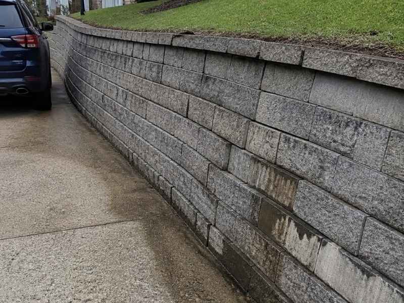 Leaning concrete block retaining wall beside a residential driveway in Madison, Alabama.